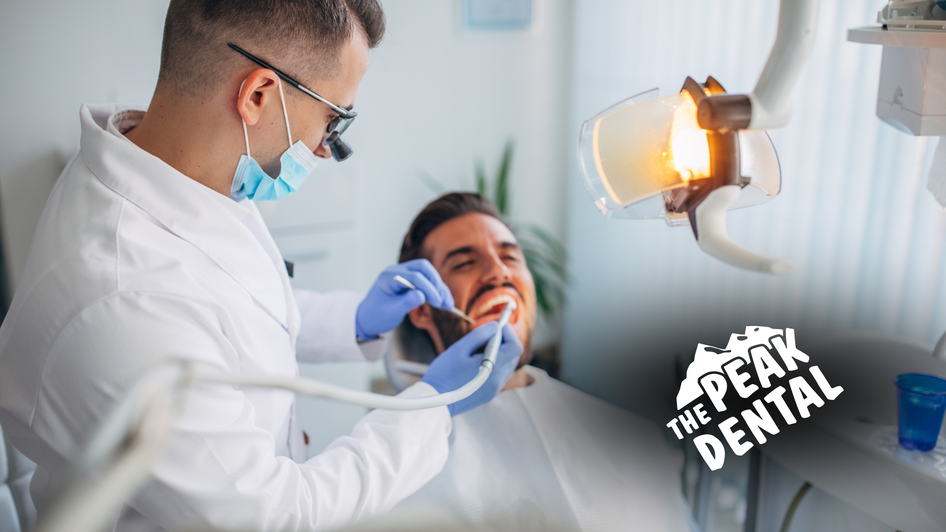 A dentist is examining a man 's teeth in a dental chair.