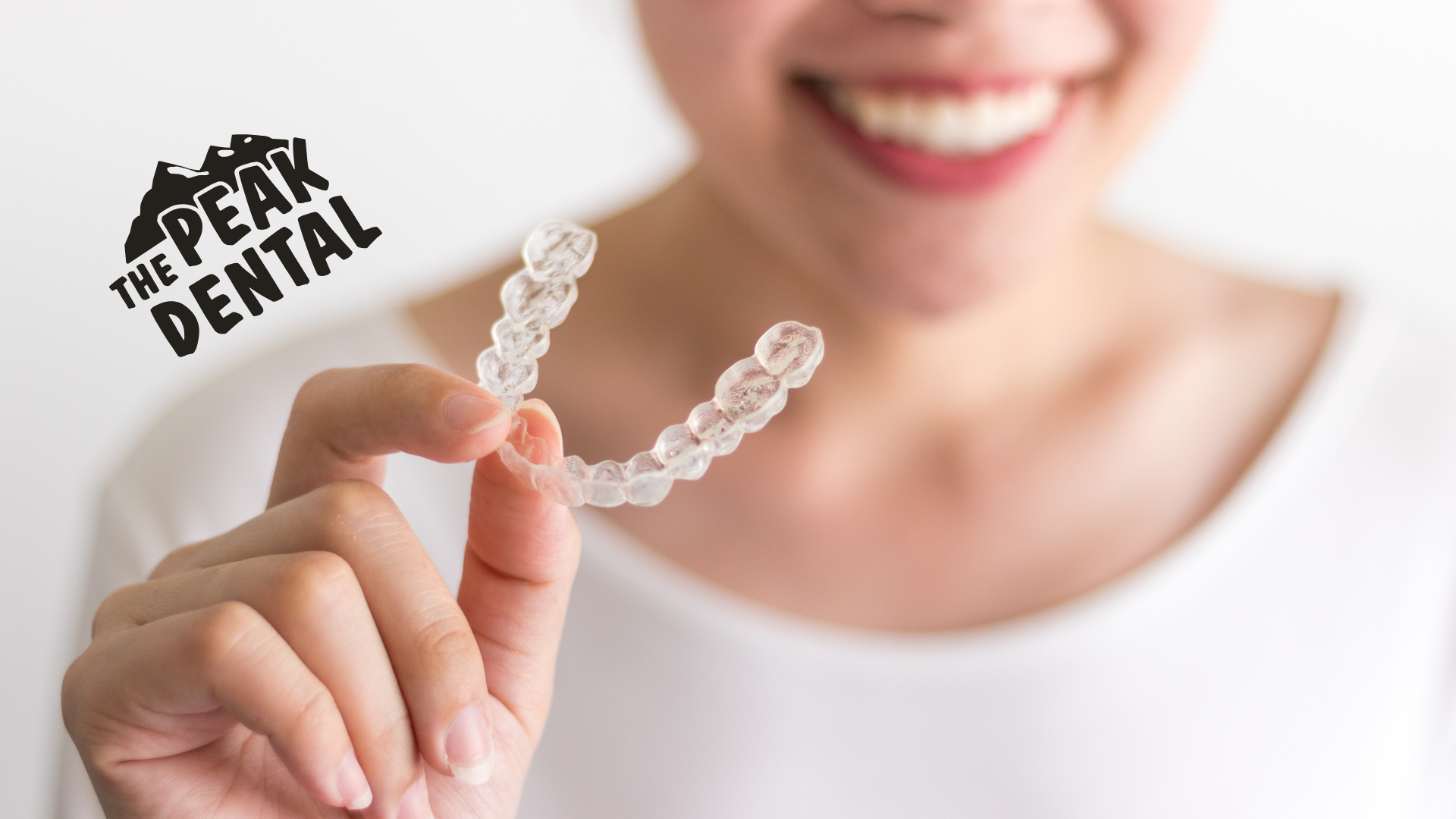 A woman is holding a clear brace in her hand.