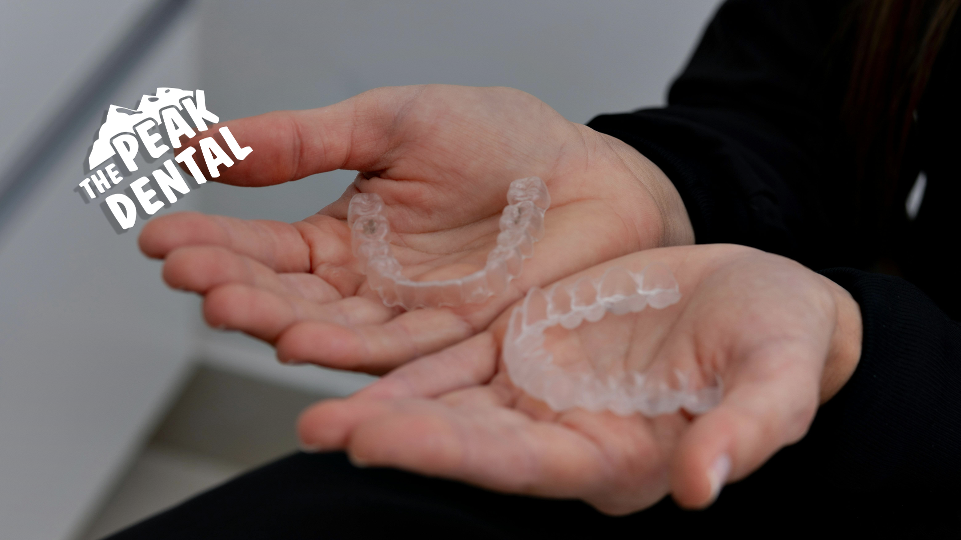 A person is holding a pair of clear braces in their hands.