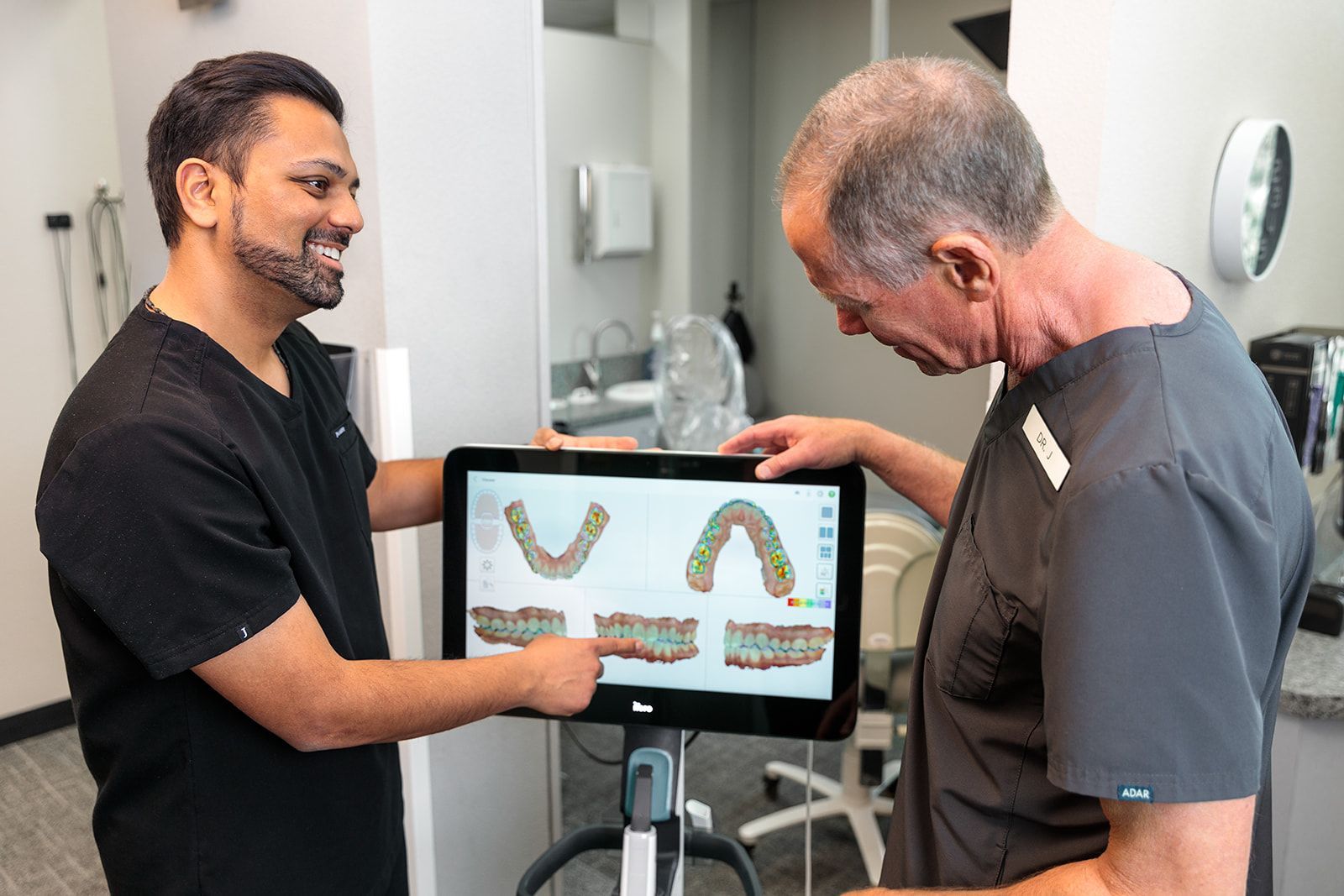 Two dentists are looking at a tablet in a dental office.