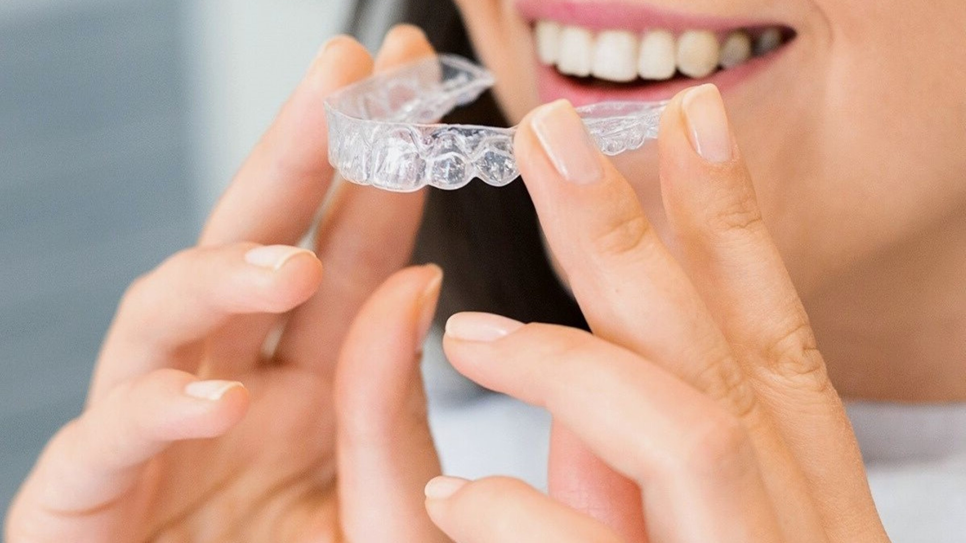 A woman is holding a clear brace in her hands.