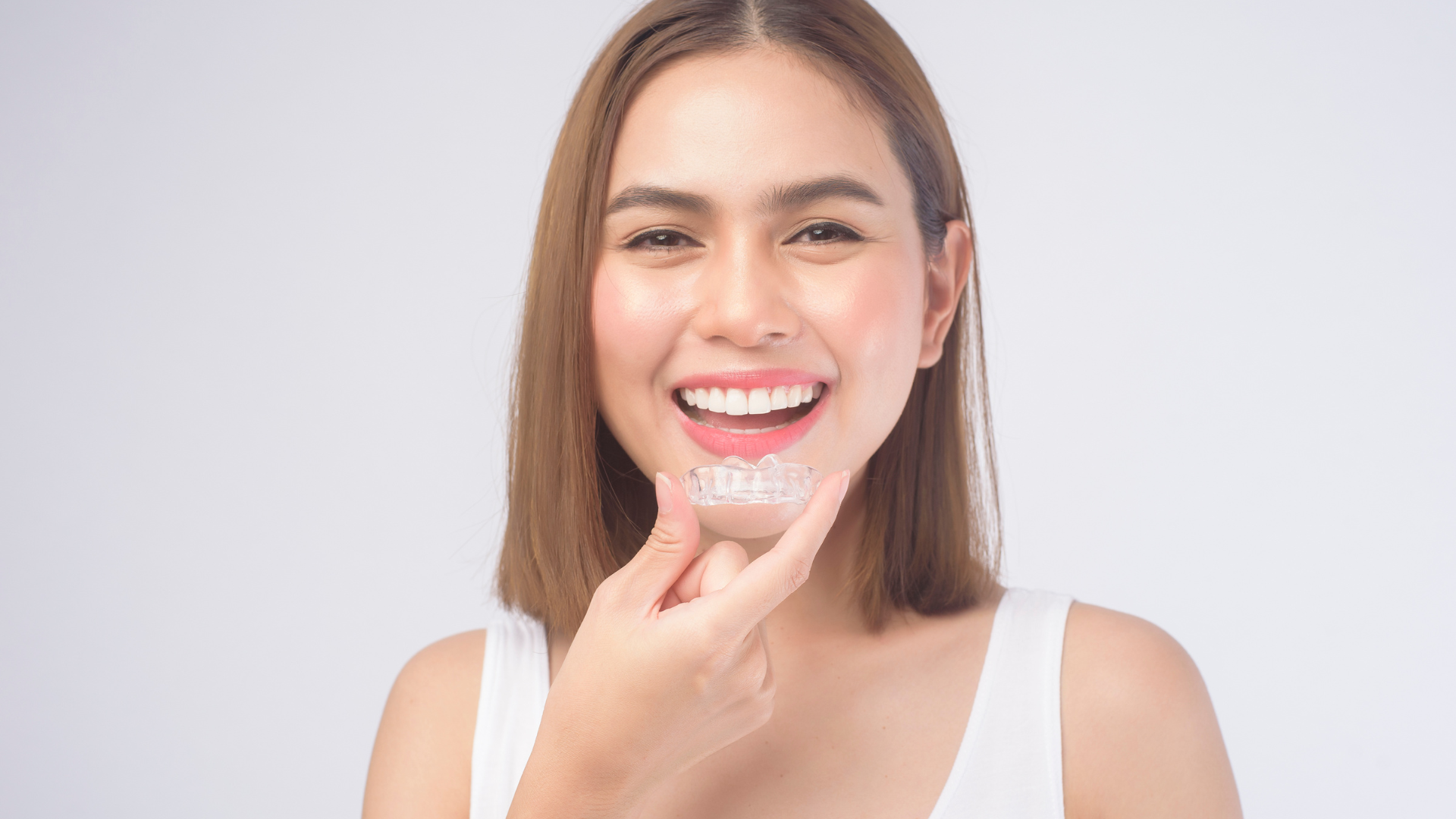 A woman is smiling with a clear brace on her teeth.