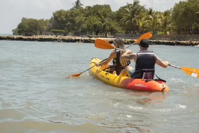 Turistas practicando kayak en el mar Caribe frente al Hotel Aimarawa, rodeados de aguas tranquilas y palmeras tropicales en la costa de San Antero.