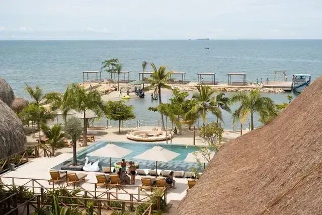 Piscina al aire libre del Hotel Aimarawa con camastros y sombrillas, rodeada de palmeras, con vista directa al mar Caribe y zona de descanso en la playa privada.