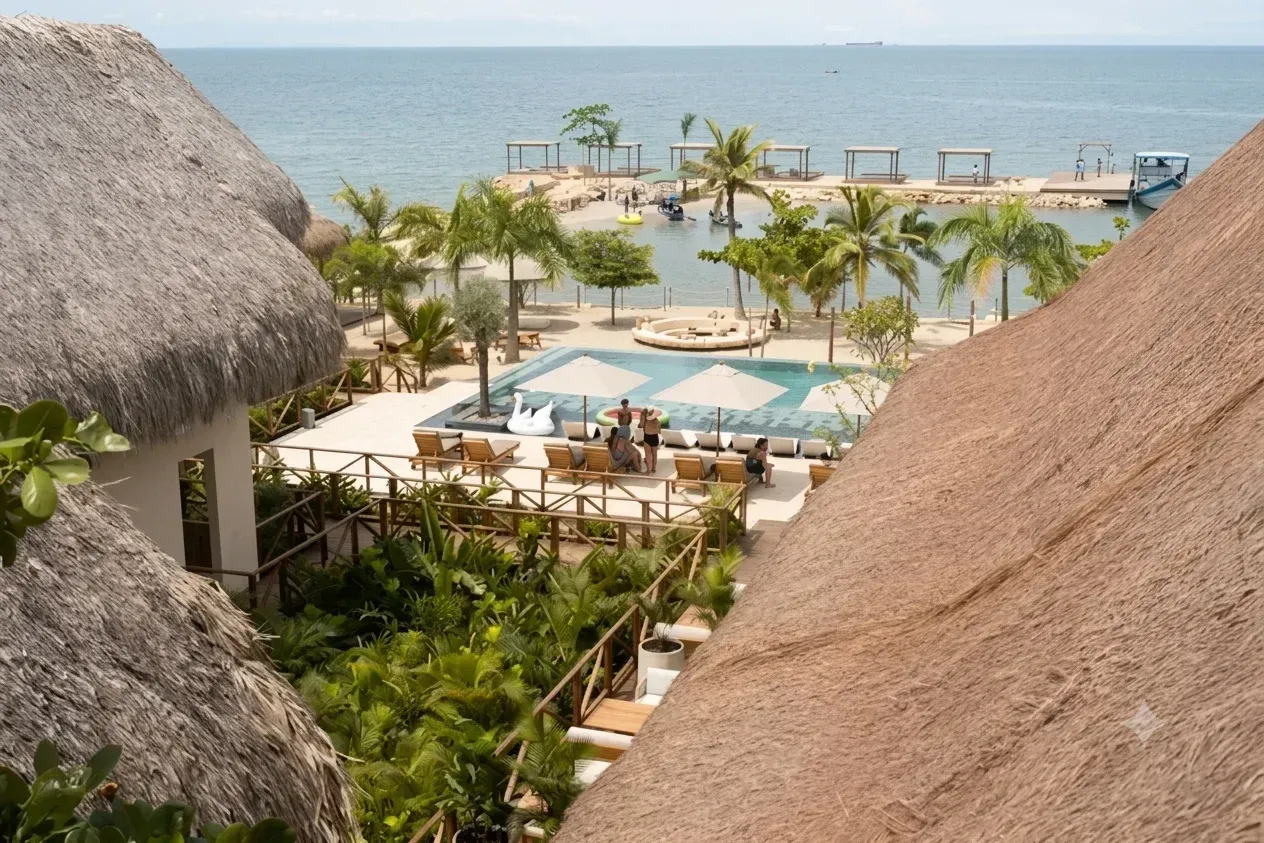 hotel en san antero frente al mar con piscina, palmeras, sombrillas, zonas de descanso y vista al agua.