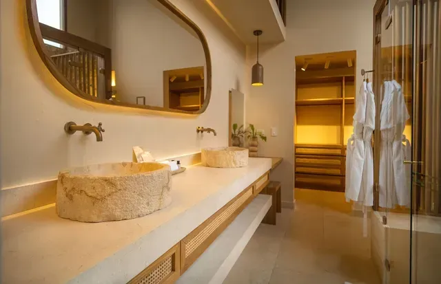Baño elegante del hotel Aimarawa con lavamanos de piedra, espejo grande y acabados naturales para una experiencia de lujo en Colombia.