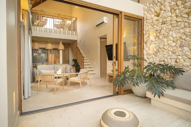 Interior de bungalow en Aimarawa Palomino con sala amplia, mezzanine y decoración en madera y piedra, perfecto para descanso en pareja o familia.
