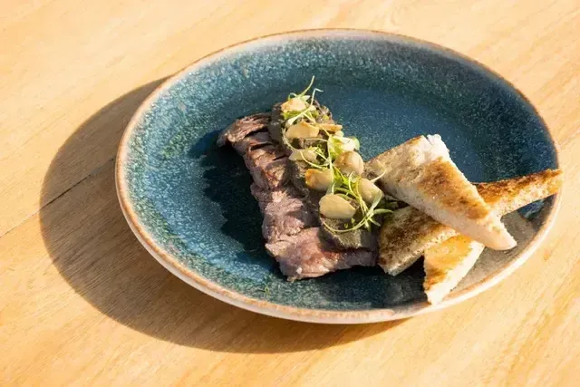 Carne sellada con champiñones frescos y pan artesanal, entrada gourmet del restaurante del Hotel Aimarawa en Punta Bolívar, experiencia gastronómica frente al mar Caribe.