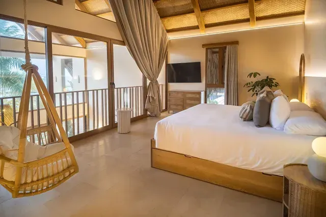 Habitación en Aimarawa Palomino con cama king size, diseño rústico y vista a la naturaleza, perfecta para una estadía romántica frente al mar.