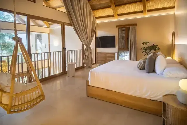 Habitación de lujo en el Hotel Aimarawa. Espacio acogedor con cama king, decoración en madera y hamaca interior, ideal para descansar en el Caribe colombiano.