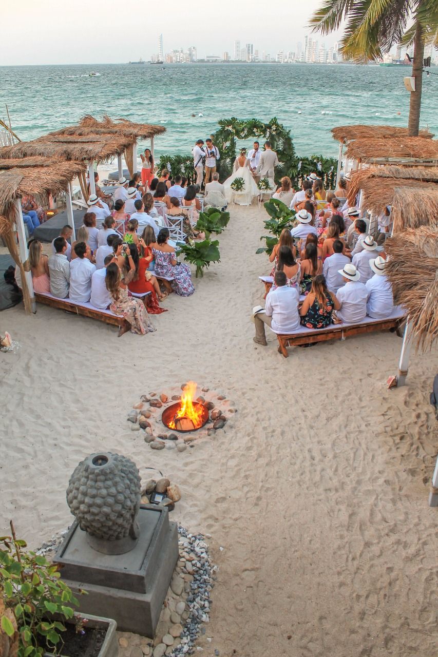 Ceremonia de matrimonio en la playa con arco de flores y fondo del mar en el Hotel Aimarawa de San Antero.