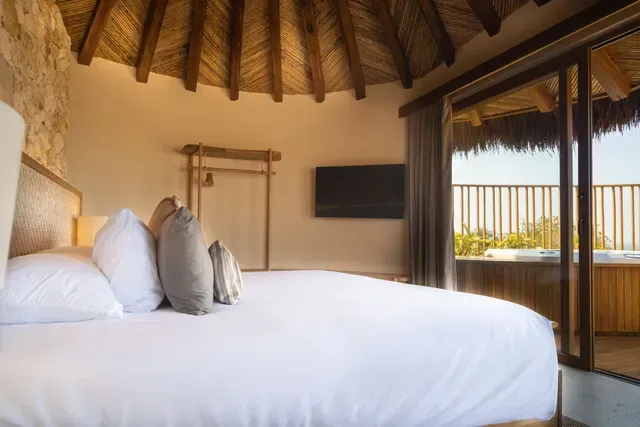 Habitación del Hotel Aimarawa en San Antero con cama king, techo en palma y acceso a terraza privada.