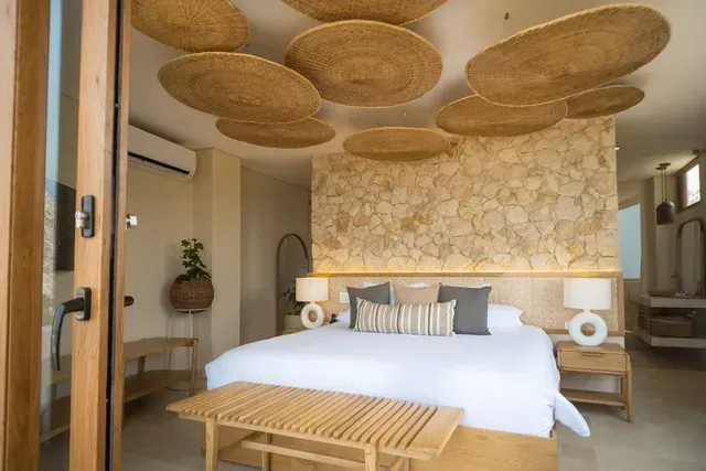 Suite del Hotel Aimarawa en San Antero con pared en piedra, cama king y decoración en tonos cálidos de inspiración natural.
