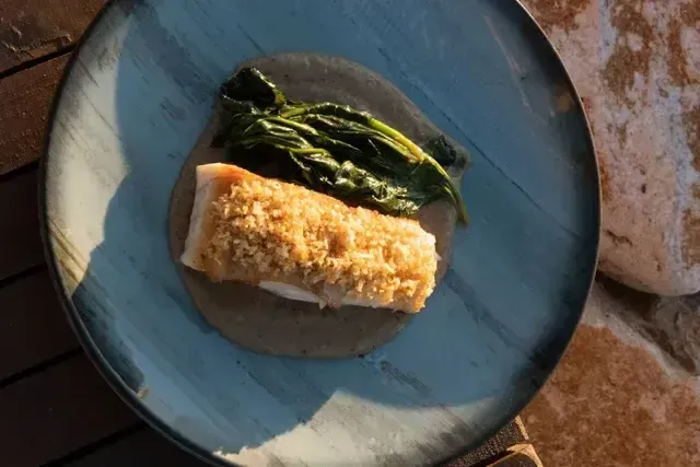Filete de pescado crocante sobre crema y acompañado de vegetales en el restaurante del Hotel Aimarawa Punta Bolívar San Antero, cocina caribeña frente al mar.