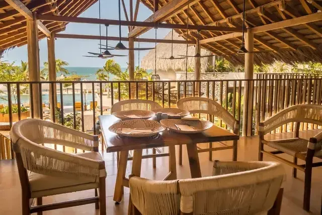 Restaurante del Hotel Aimarawa en San Antero con mesas de madera, sillas artesanales y vista al mar Caribe para disfrutar de gastronomía de lujo.