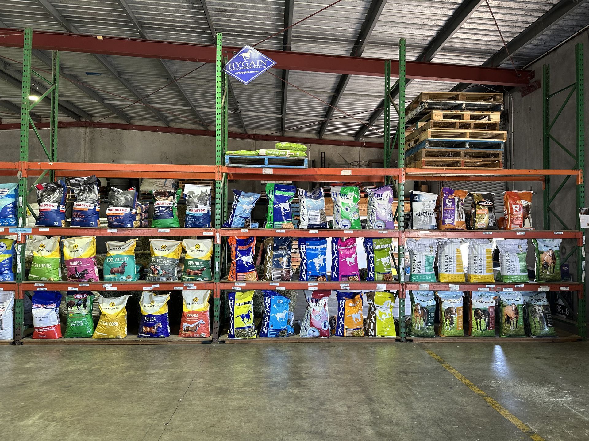 Shelves stocked with various brands of dog food bags in a warehouse setting. — North Coast Stock Feeds in Wardell, NSW