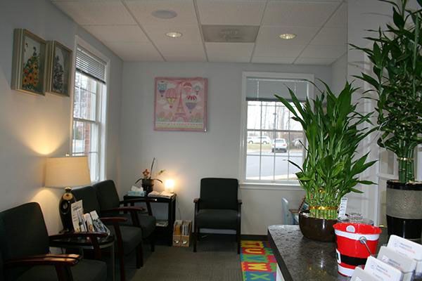 a waiting room with black chairs and plants