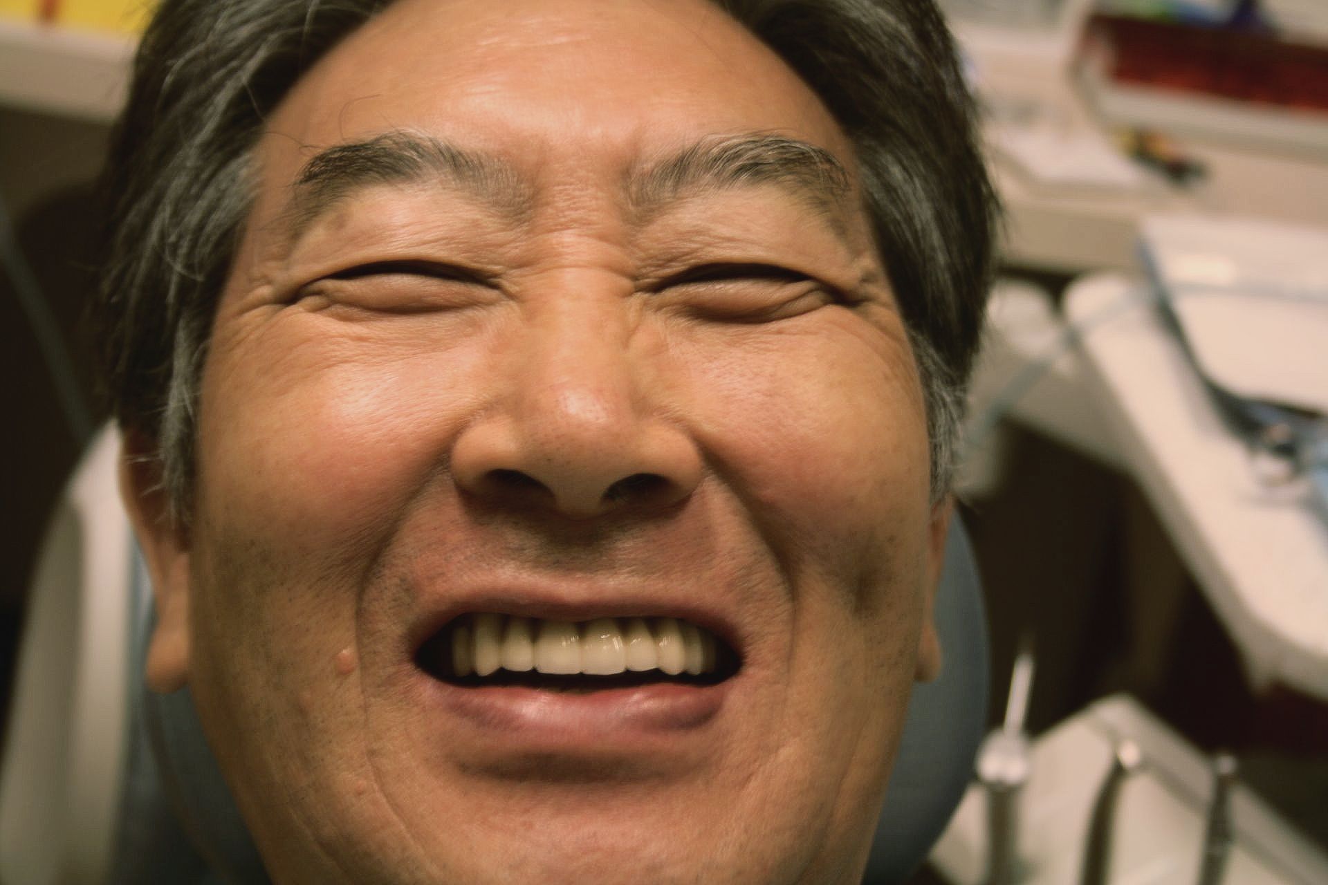 a man is smiling in a dental chair with his eyes closed .