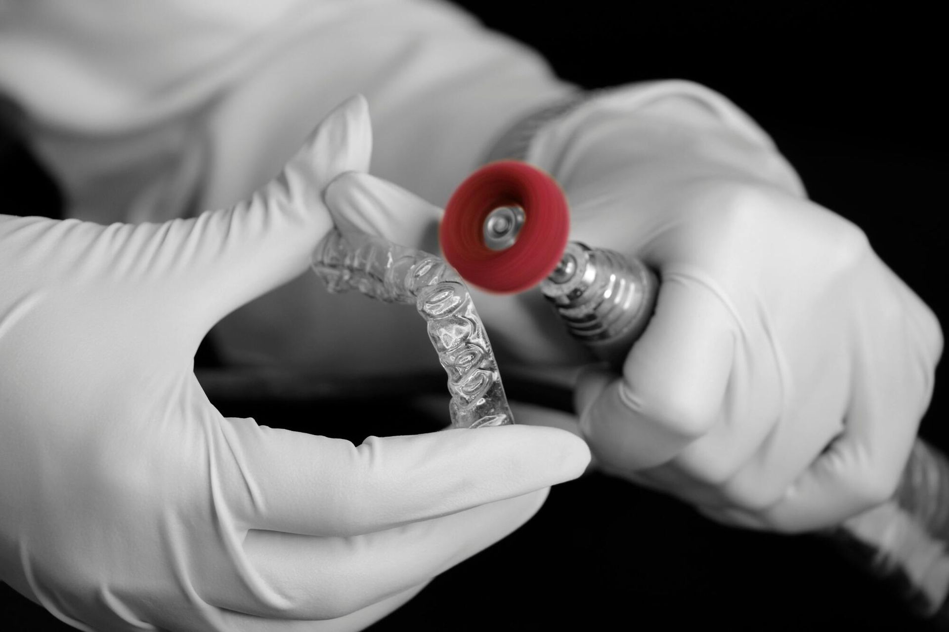Gloved hands adjusting a red medical fitting on a silver tube or hose