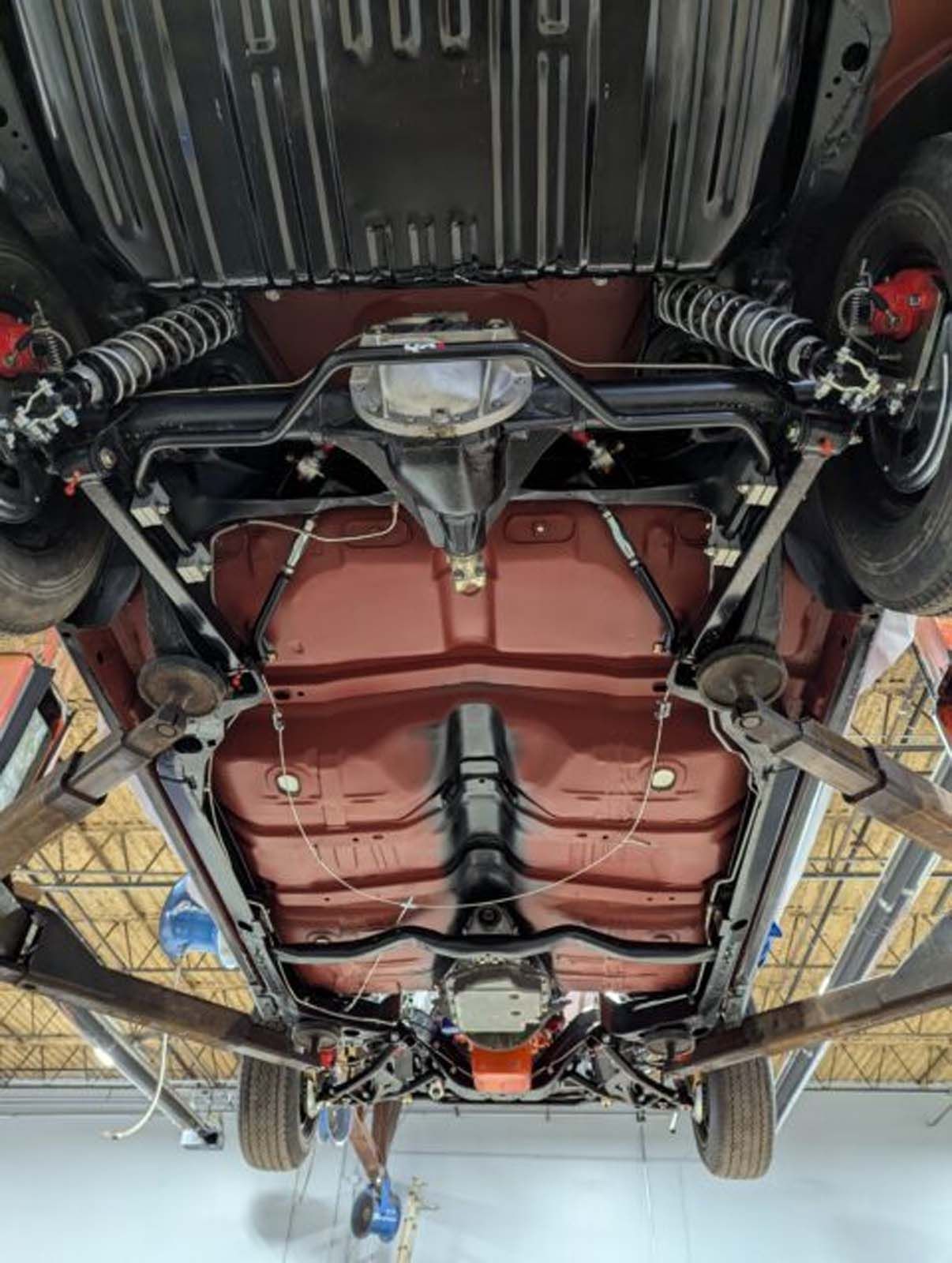 The underside of a car is shown in a garage.