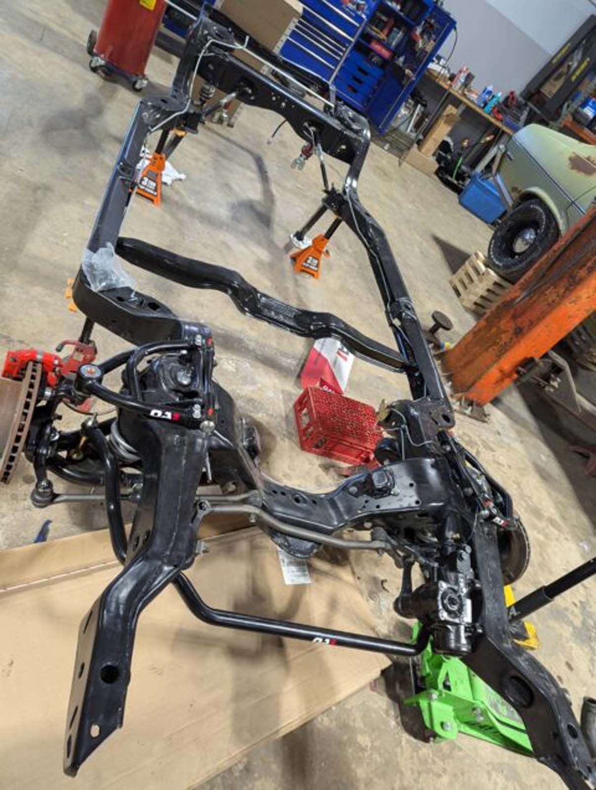 A car frame is sitting on top of a cardboard box in a garage.