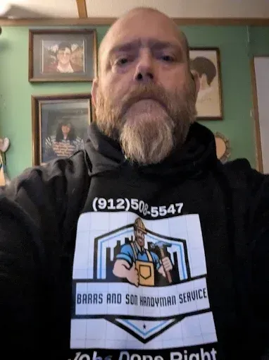 A person with a beard wearing a black hoodie with a logo for 