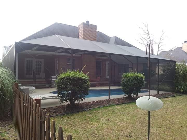 A backyard view of a house with a brick exterior and a large screened-in pool patio area.