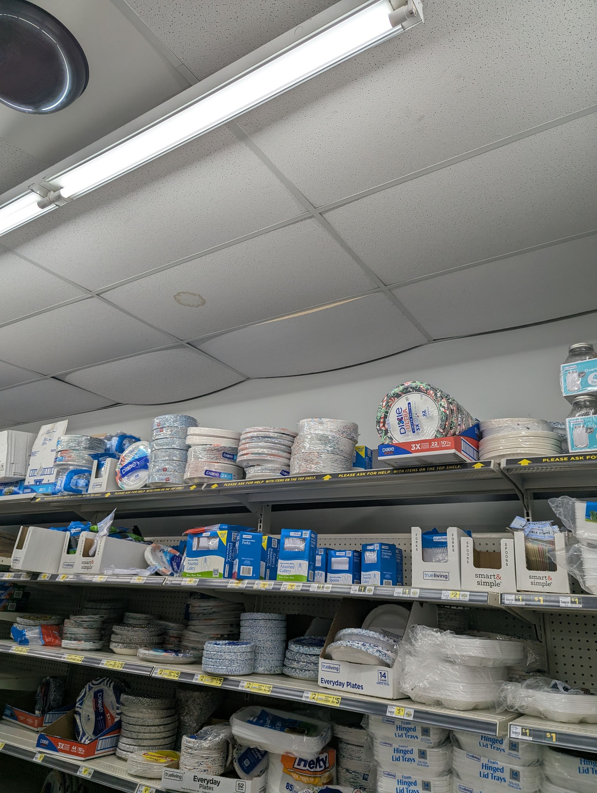 Store shelves stocked with various packages of disposable paper plates, bowls, and napkins.