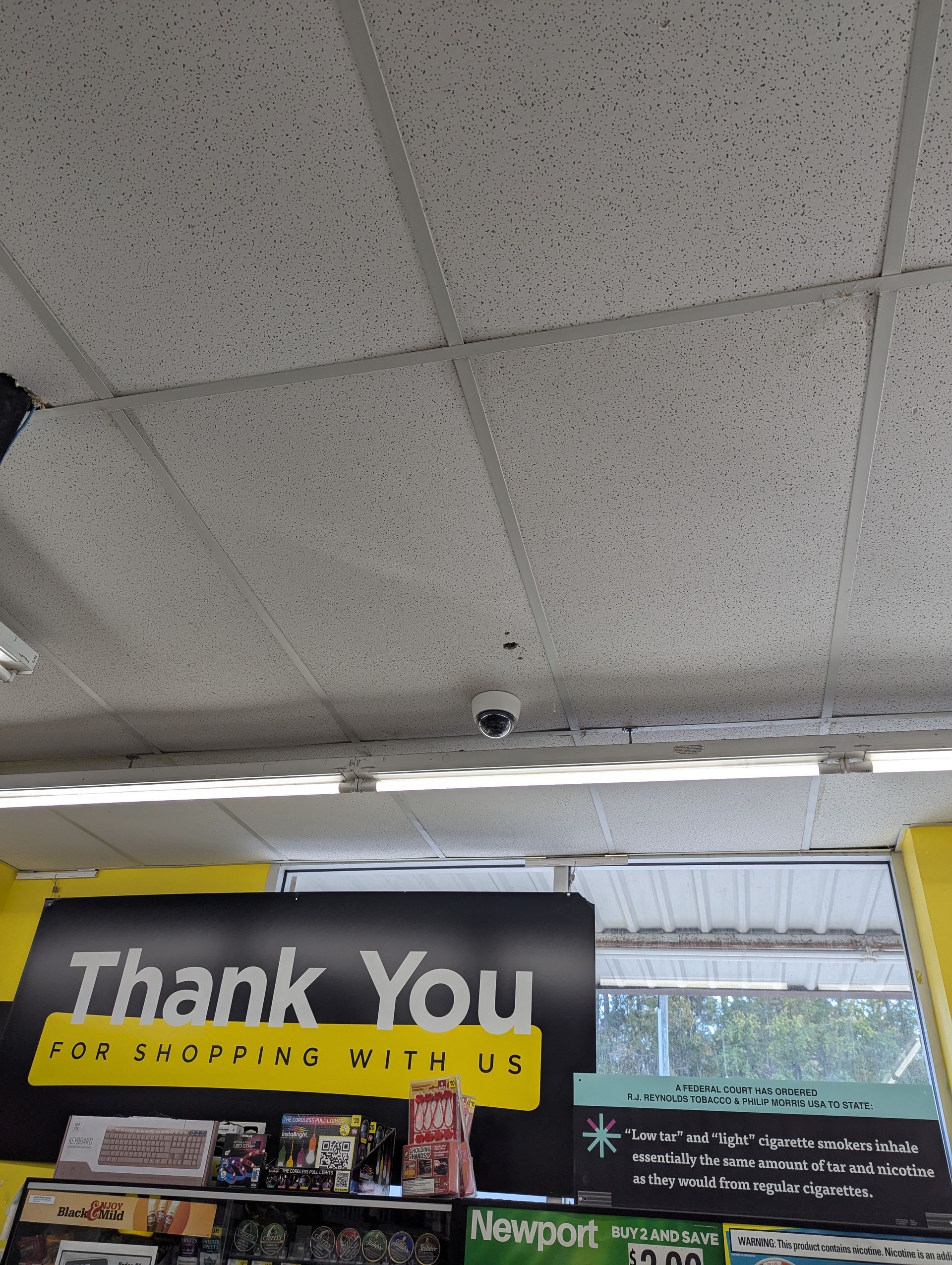 A storefront interior view showing a ceiling-mounted security camera above a yellow and black 