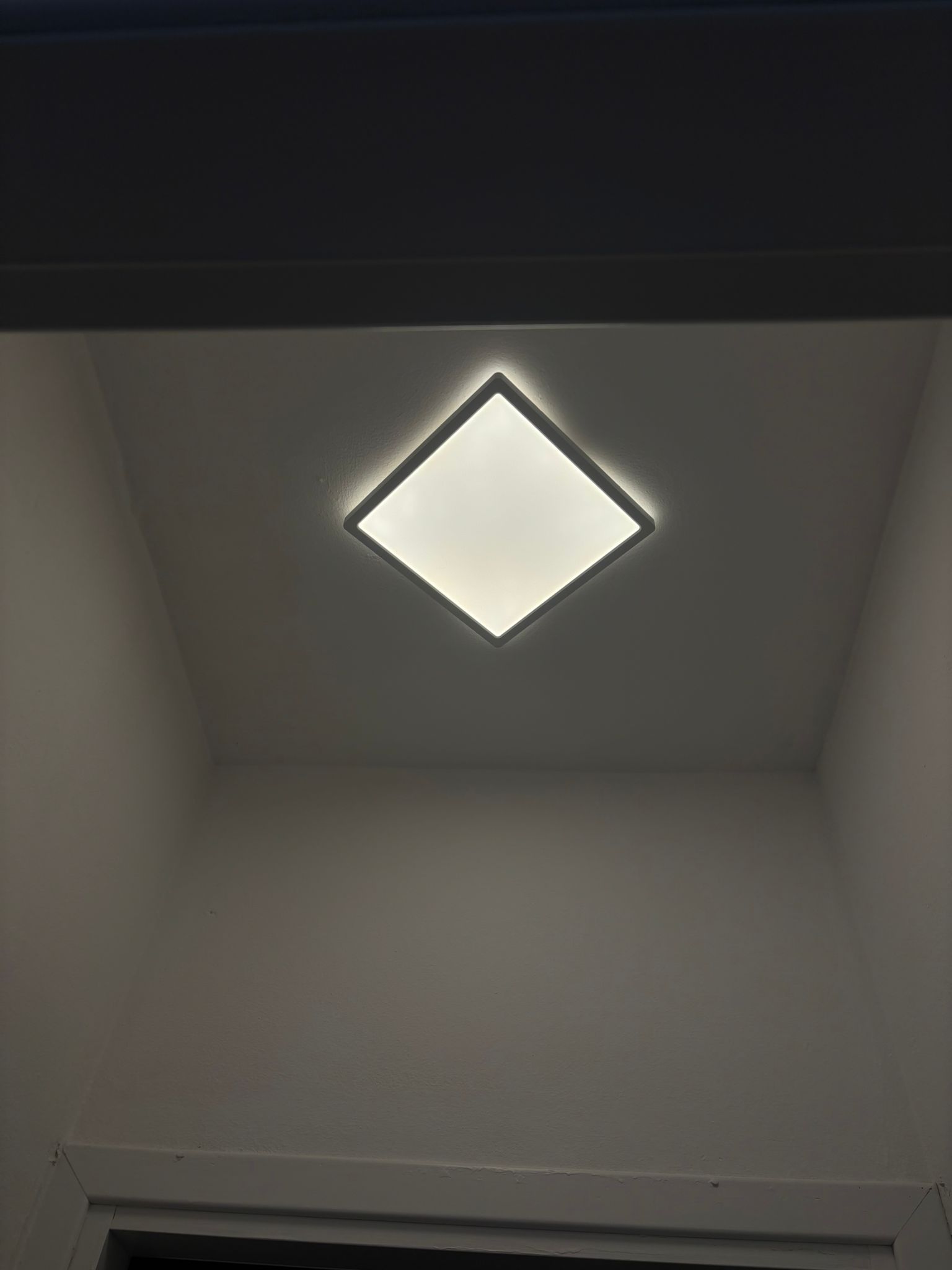 Un lampadario quadrato è appeso al soffitto di una stanza.