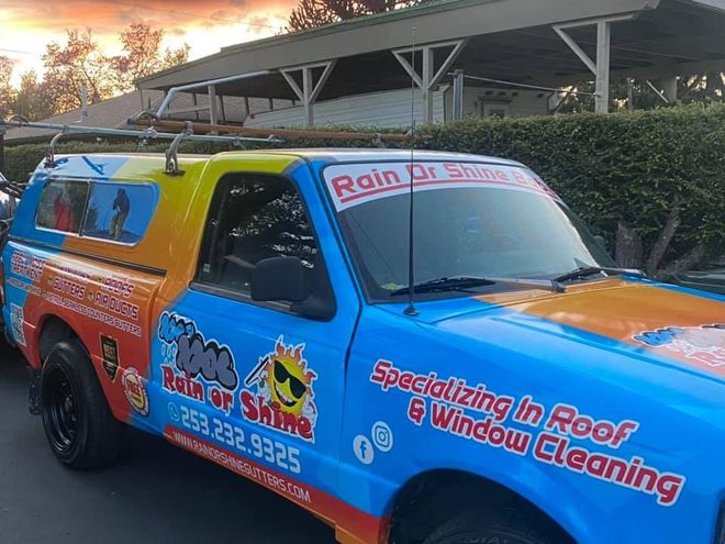 A blue truck that says rain or shine specializing in roof and window cleaning