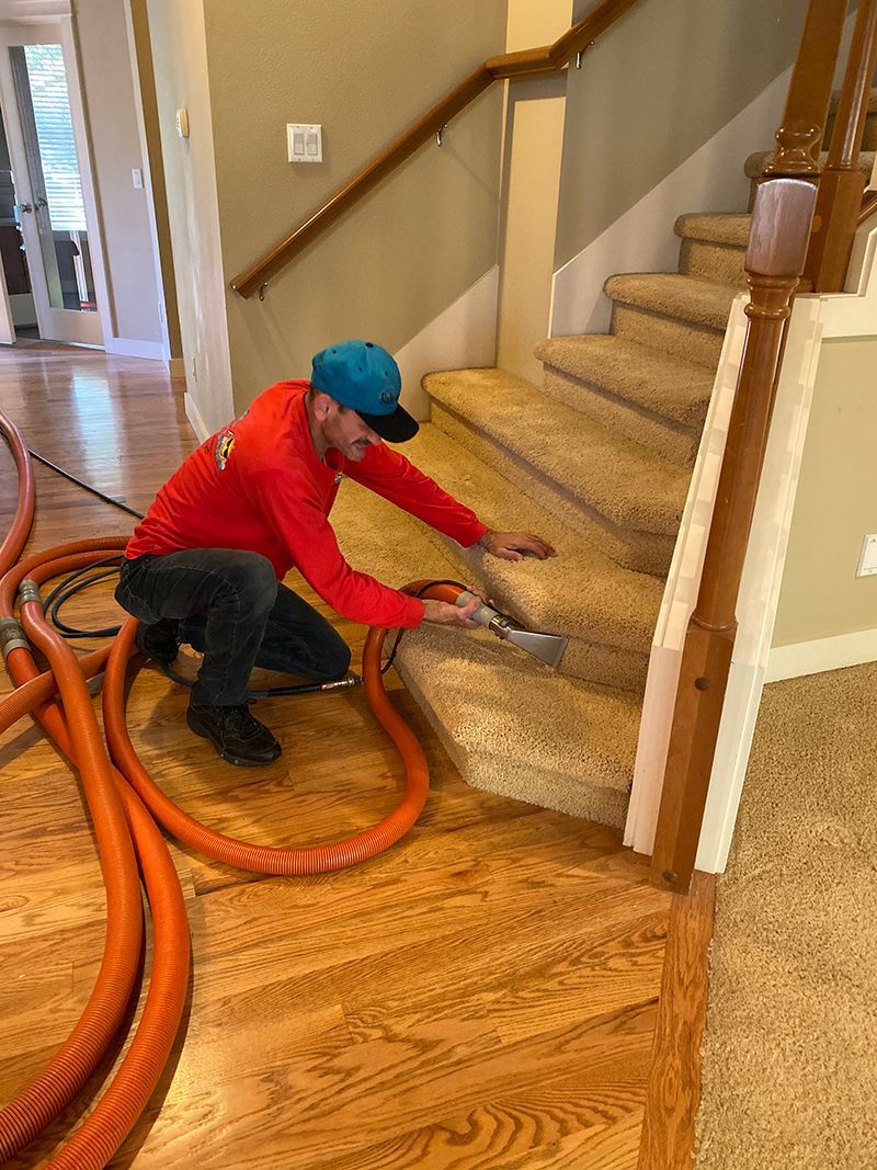 A man is cleaning a carpeted staircase with a vacuum cleaner.
