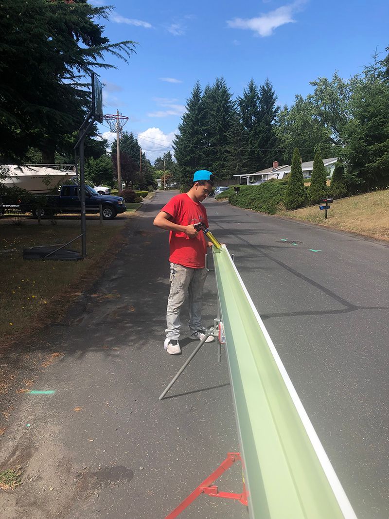 A man is standing next to a green fence on the side of the road.