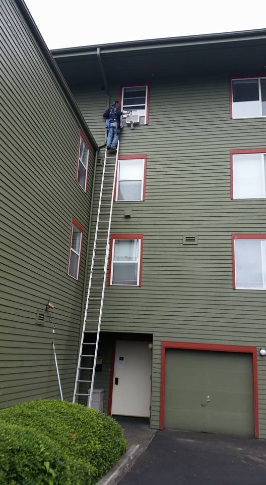 A man is standing on a ladder on the side of a building.