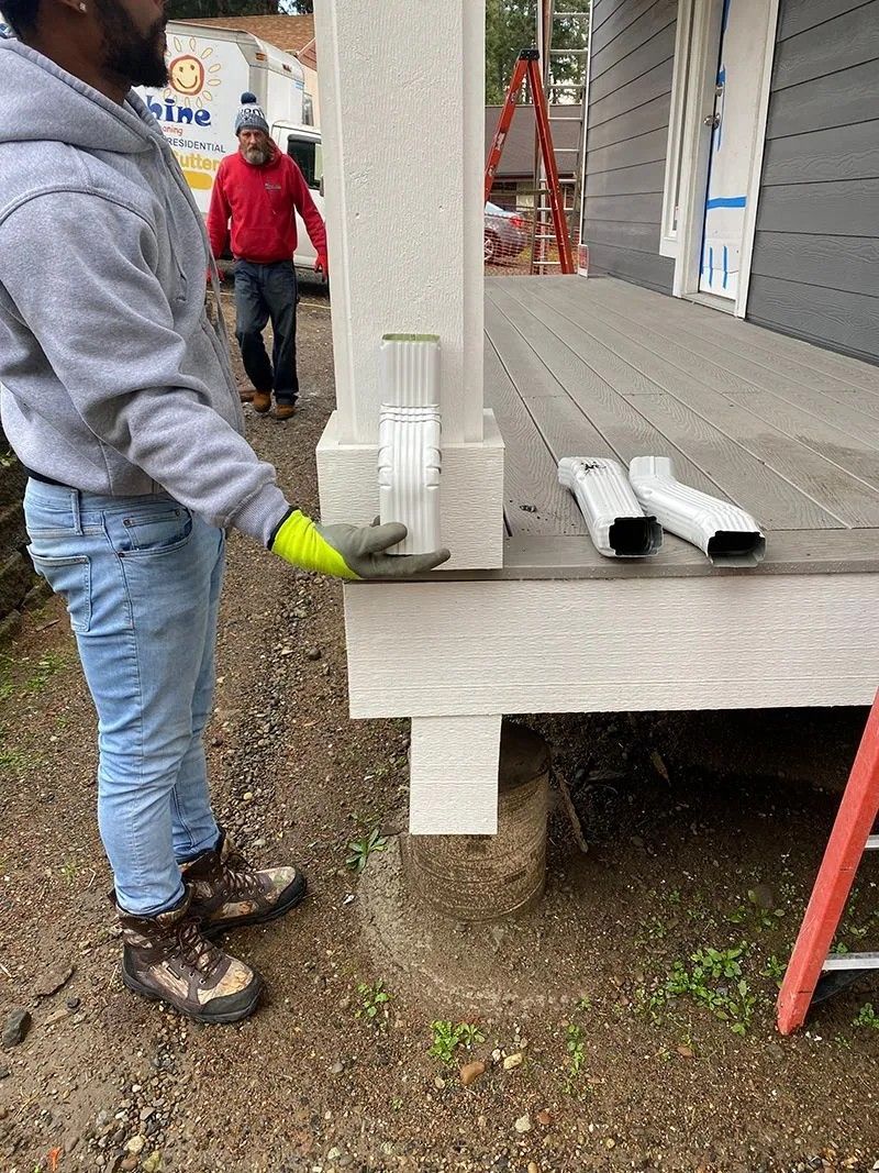 A man is working on a porch with a ladder in the background.