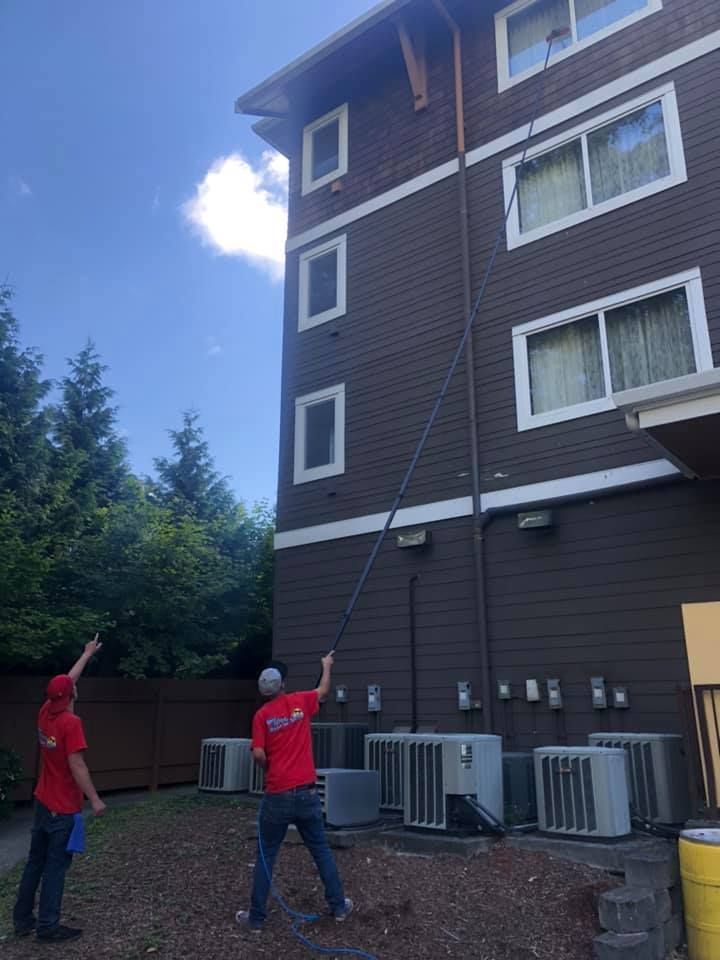 Two men are cleaning the side of a building.