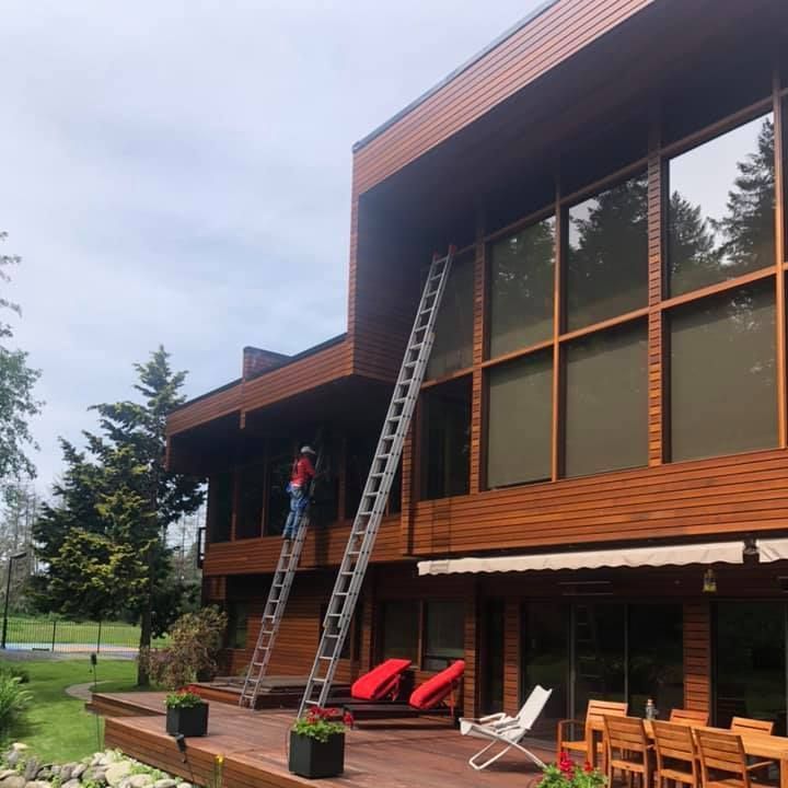 A man is standing on a ladder on the roof of a house.