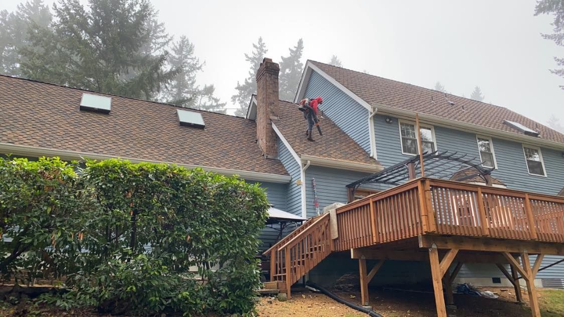 A man is standing on the roof of a house with a deck.