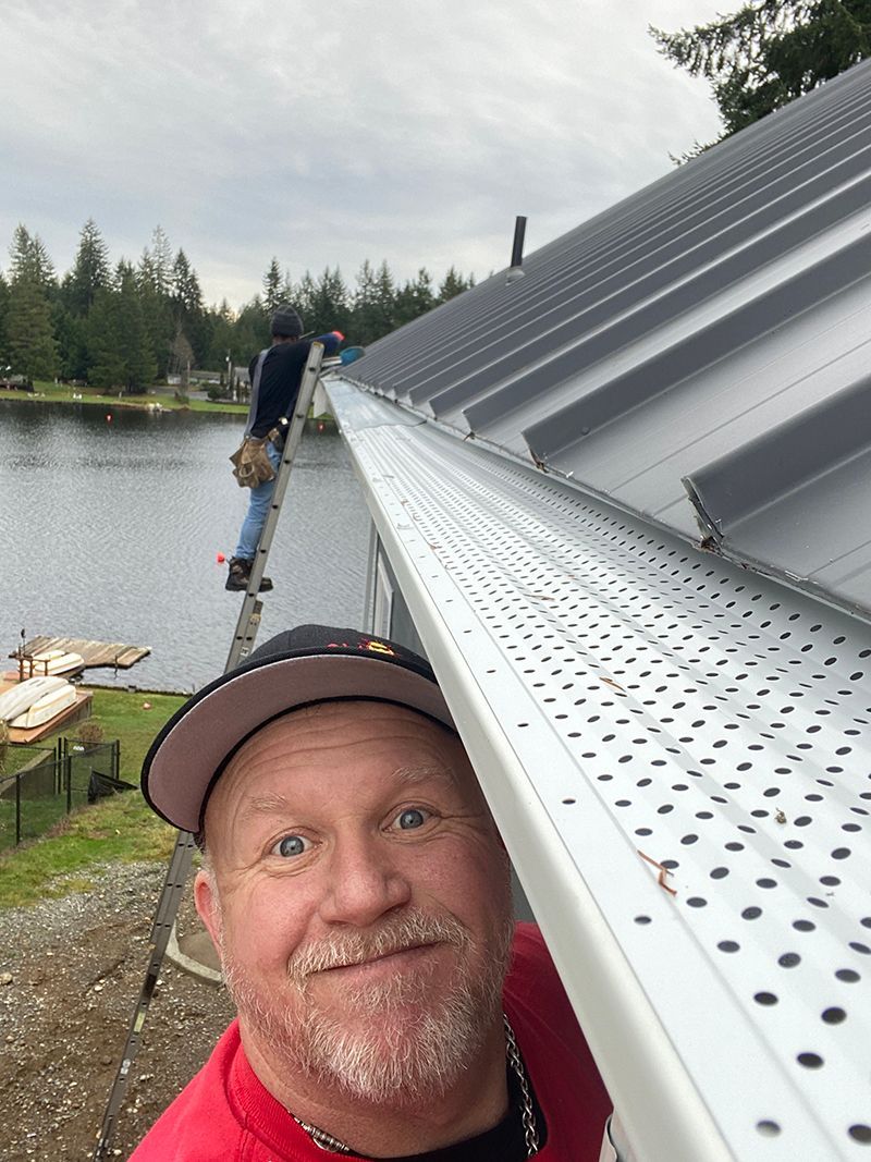 A man is standing next to a gutter on a roof.
