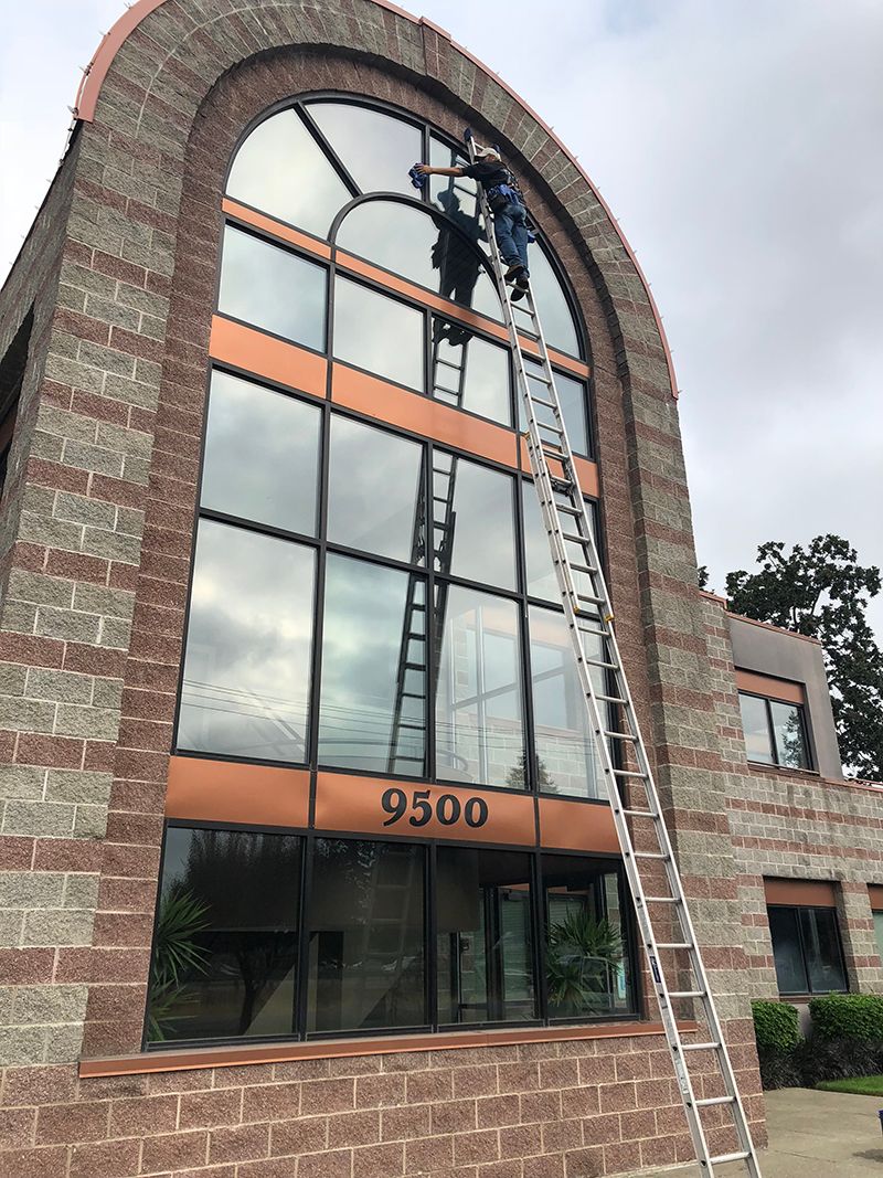 A man is cleaning the windows of a brick building.