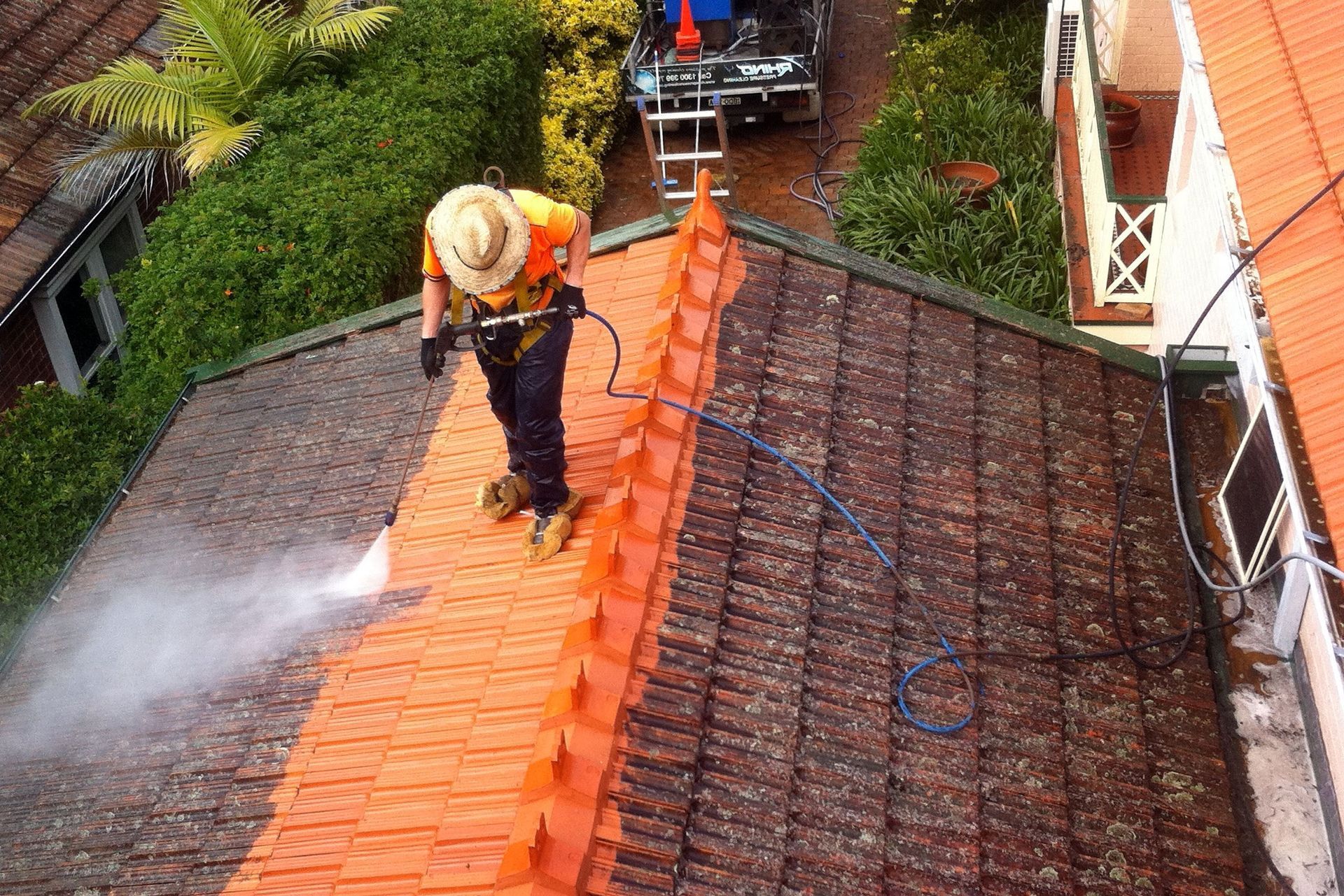 A man is cleaning a roof with a high pressure washer.