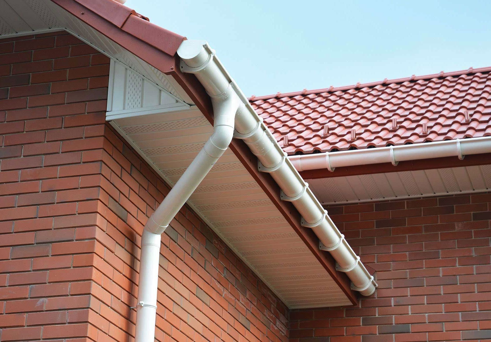 A brick building with a red roof and white gutters