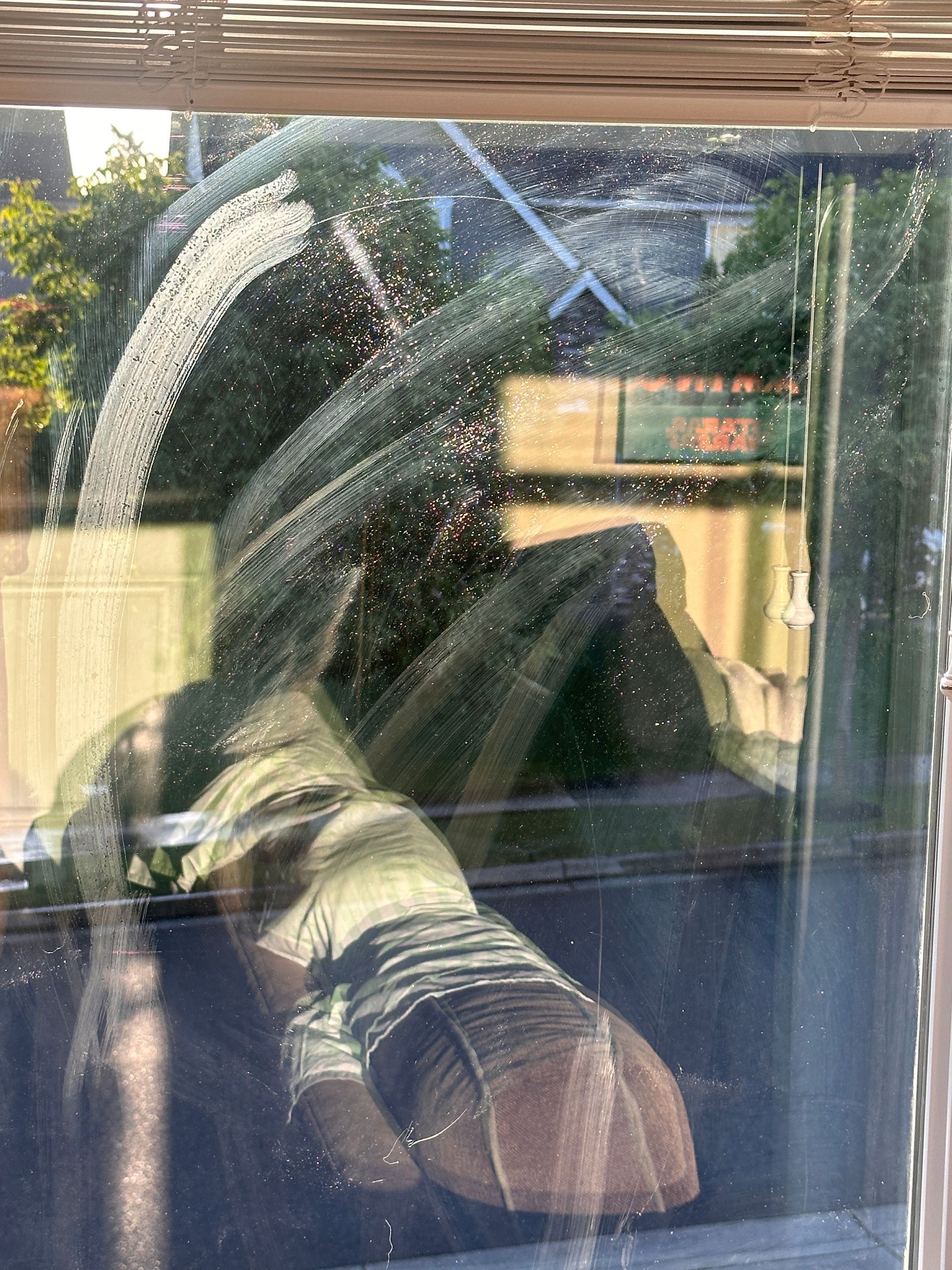 A person is standing in front of a window with a reflection of a person in the window.