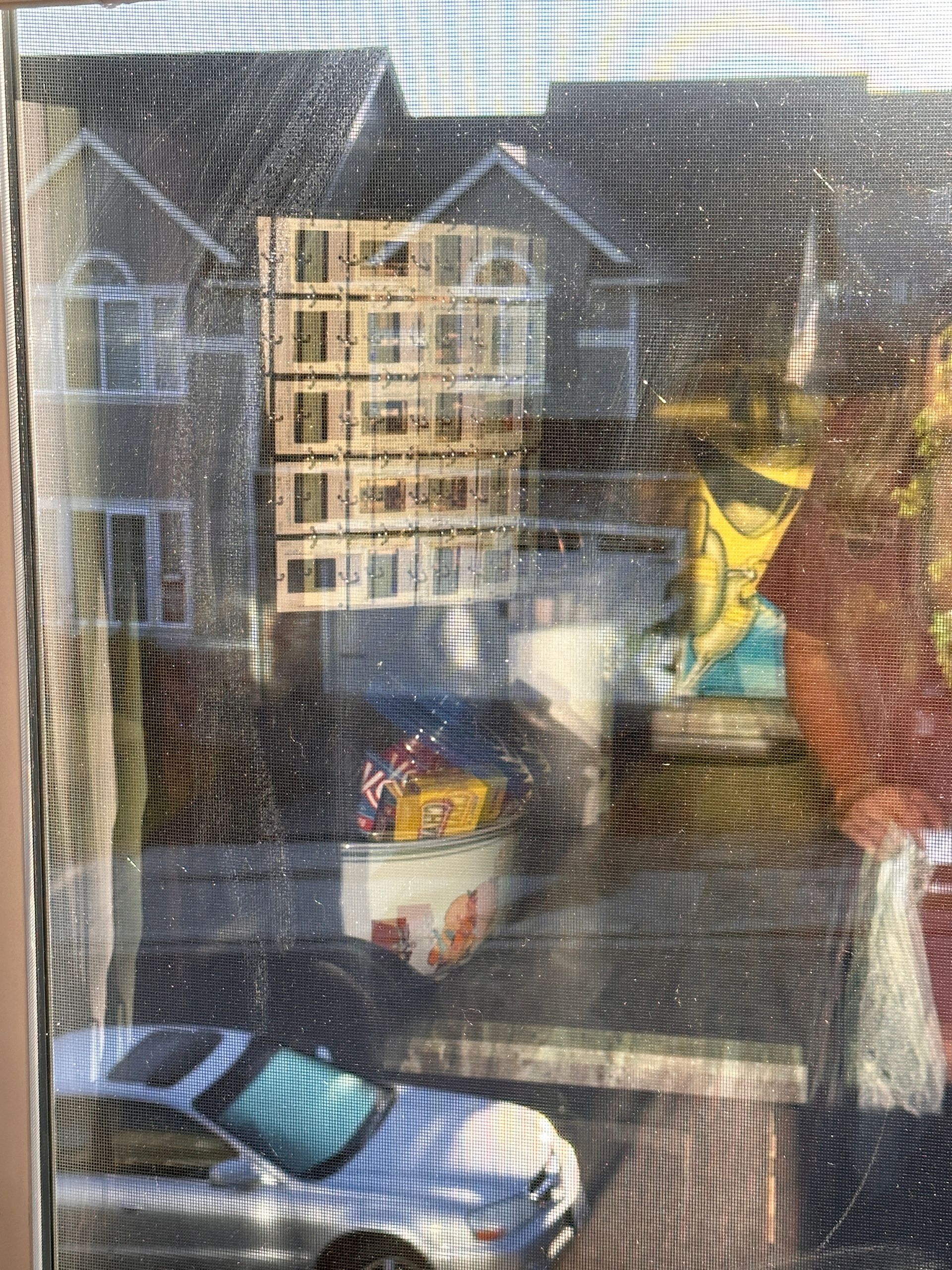 A car is parked in front of a window with a screen.