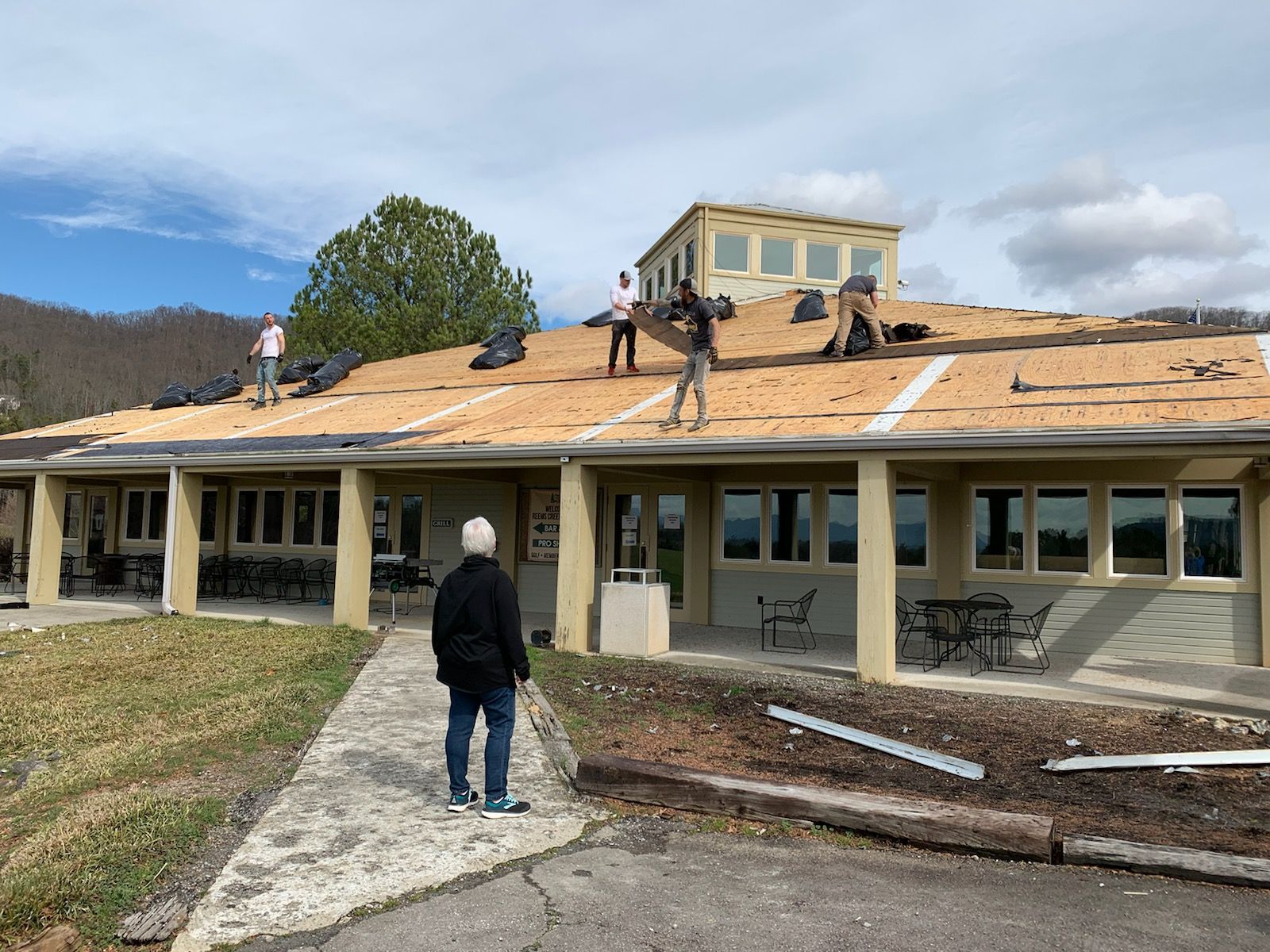 A group of people are working on the roof of a building. Reems Creek Golf Club.