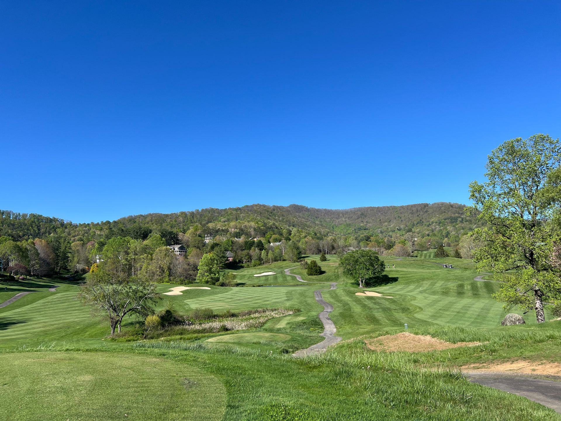 A golf course with trees and mountains in the background on a sunny day. Reems Creek Golf Club. Weaverville, North Carolina.