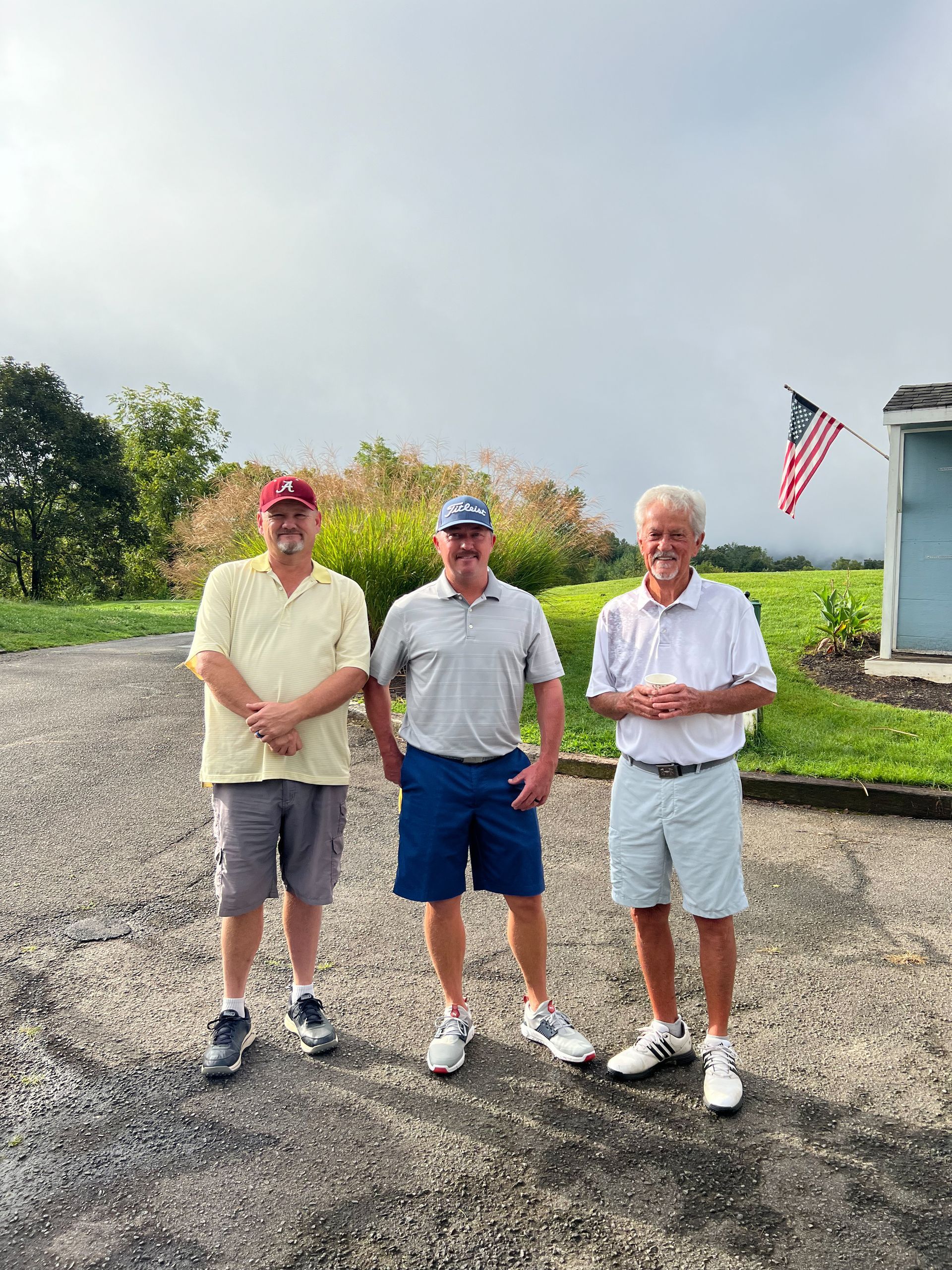 Three men are standing next to each other on a gravel road. Reems Creek Golf Club. Weaverville, North Carolina.