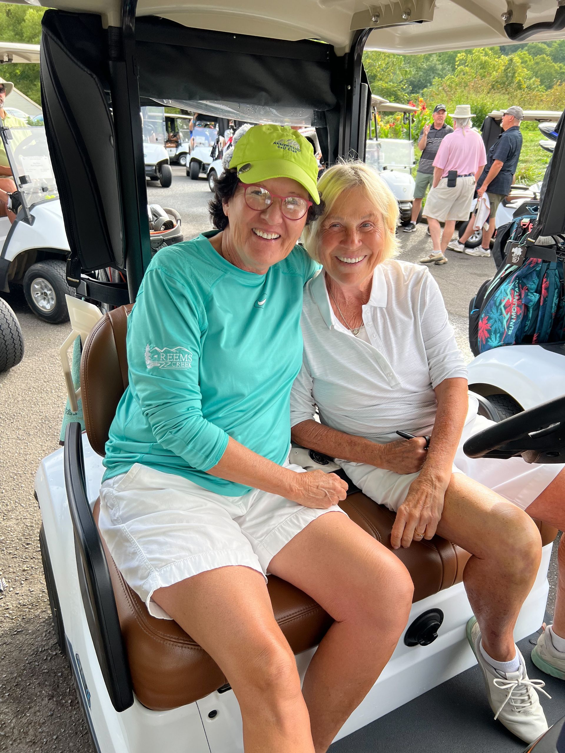 Two women are sitting in a golf cart and smiling for the camera. Reems Creek Golf Club. Weaverville, North Carolina.