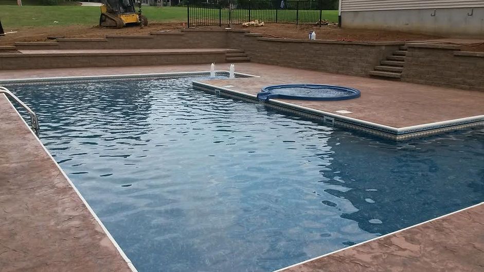 A large swimming pool with a lawn mower in the background