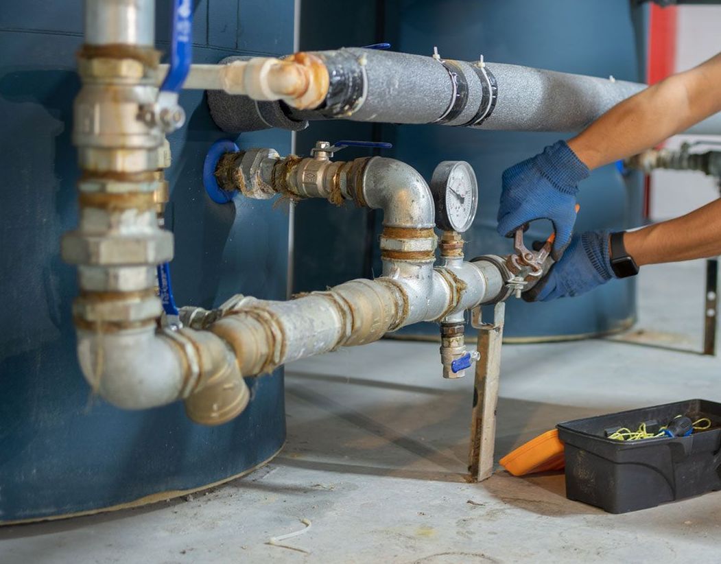 A plumber is working on a pipe in a building.